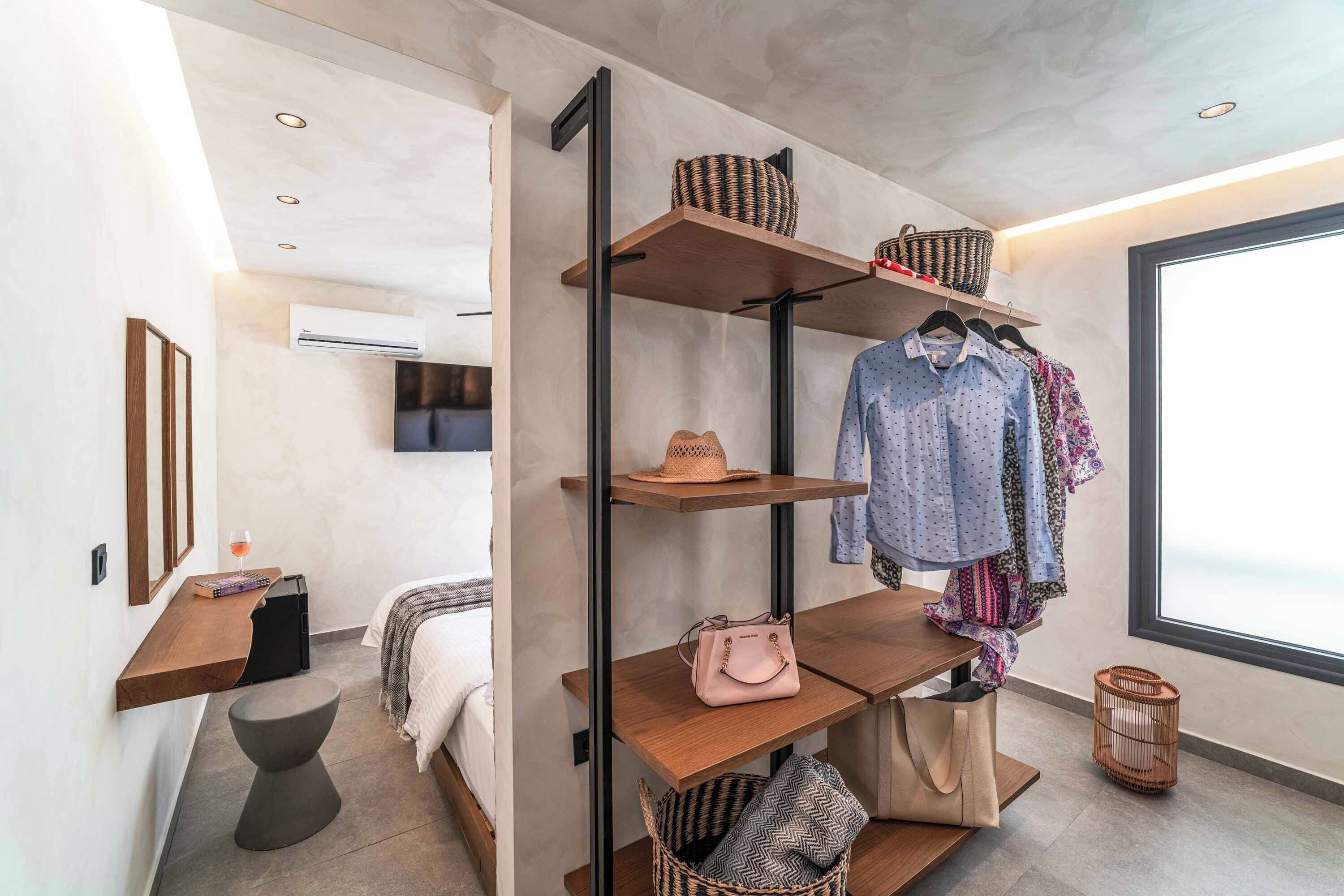 Een moderne slaapkamer met een inbouwkast, nachtkastje, stoel en een groot raam.