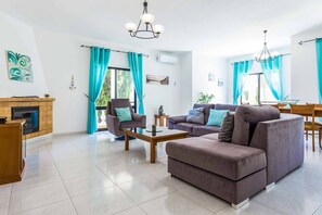 A modern living room with a fireplace, two sofas, a coffee table, and a dining area with a table and chairs. - Villa Bonita Gale - Three Bedroom Villa, Sleeps 6 (Vale Rebelho)
