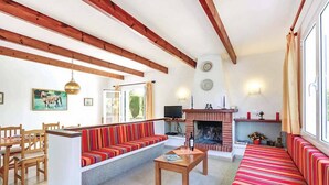 A spacious living room with wooden beams, a fireplace, a television, and a dining area with wooden furniture. - Villa Bini Beatriz - Two Bedroom Villa, Sleeps 4 (Binibeca)