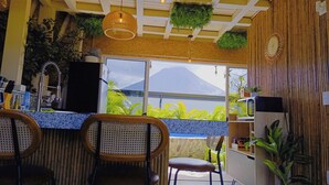 Un restaurant offrant une vue sur la montagne, avec un bar doté de tabourets, de plantes suspendues et d’un plafond en bois.