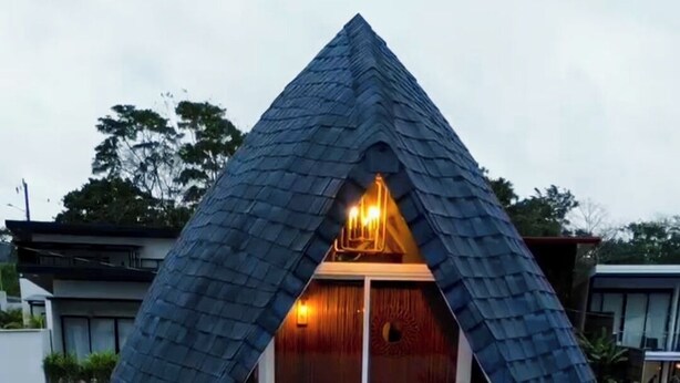 Une maison dotée d’un toit triangulaire original, d’un balcon et d’une piscine.