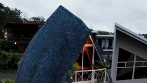 Une maison moderne dotée d’une structure sphérique originale, d’un balcon avec piscine et d’une végétation luxuriante.