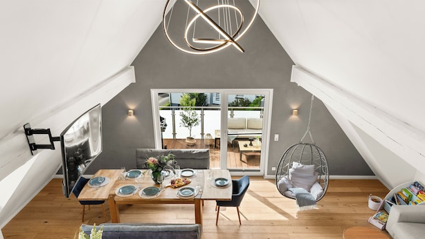 Een modern loftappartement met een eethoek, een hangstoel en een bank.