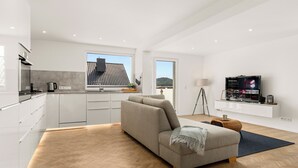 Een modern interieur met een bank, een salontafel, een televisie en uitzicht op het buiten.