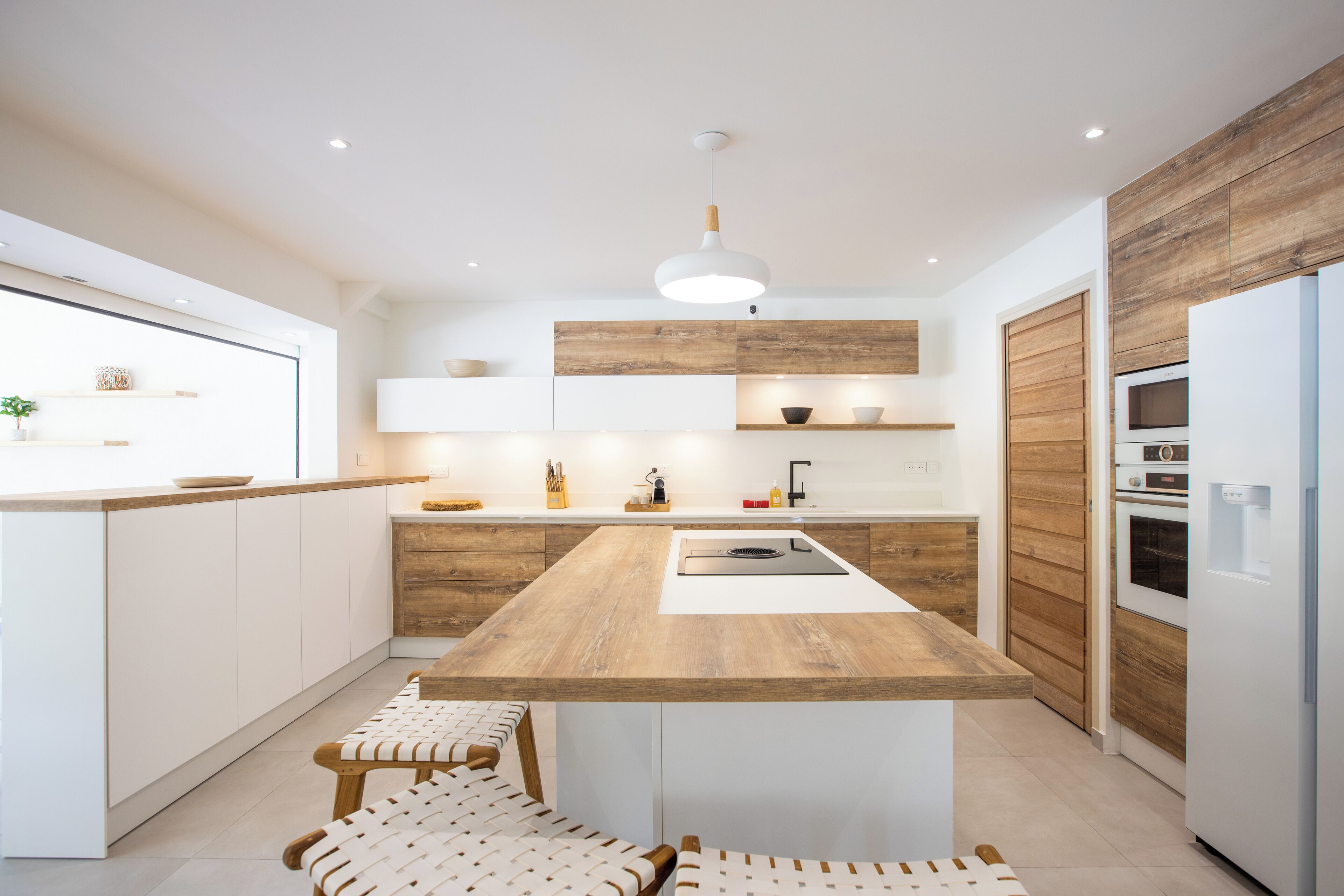 A modern kitchen with a central island, wooden cabinetry, and a built-in oven.