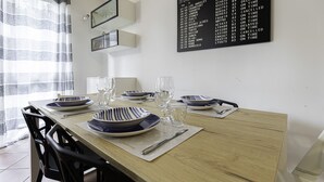 A dining table set with blue and white striped plates, clear glasses, and cutlery, with a black flight information board on the wall. - Villa Donatori (Lesmo)