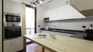 A modern kitchen with stainless steel appliances, a wooden table, and a tiled backsplash. - Villa Donatori (Lesmo)