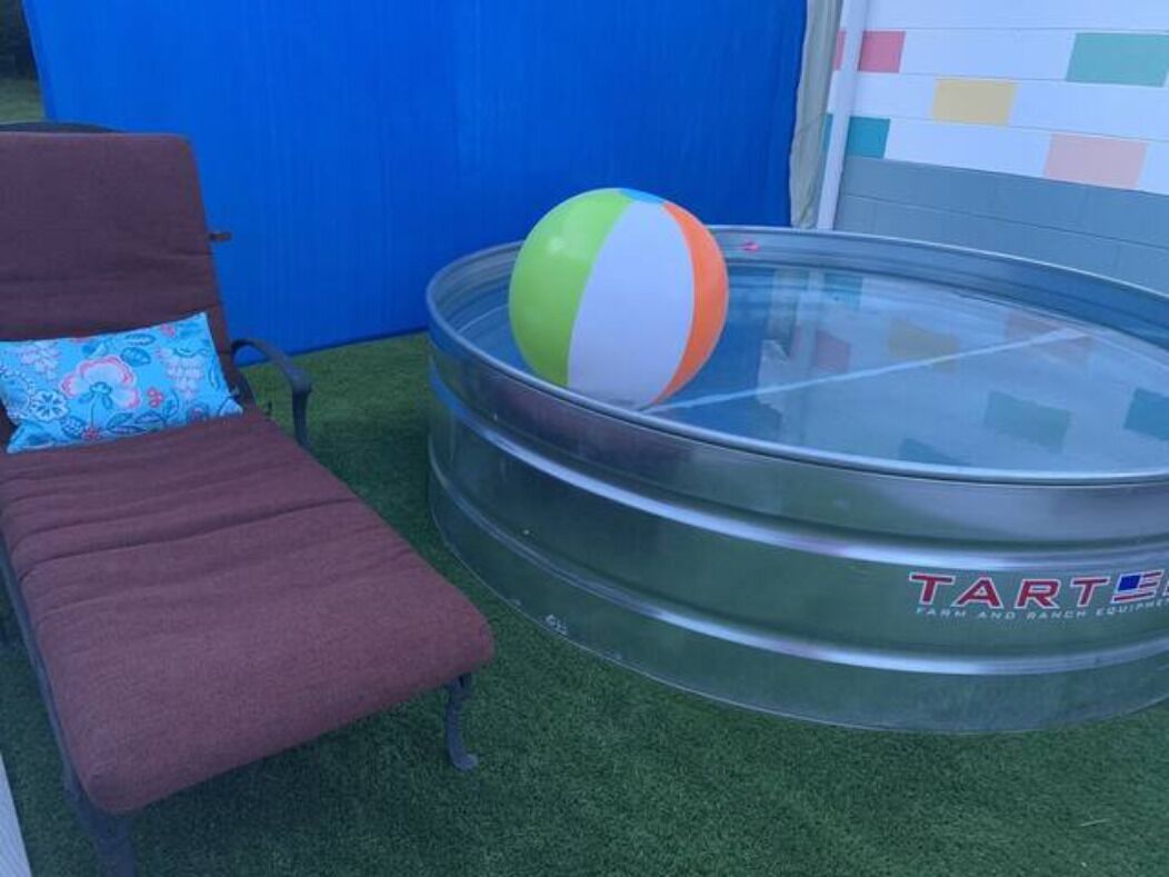 Una piscina con una pelota de colores, una tumbona y una pared azul.