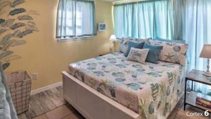 A bedroom with a bed, curtains, a nightstand, and a wall decoration.