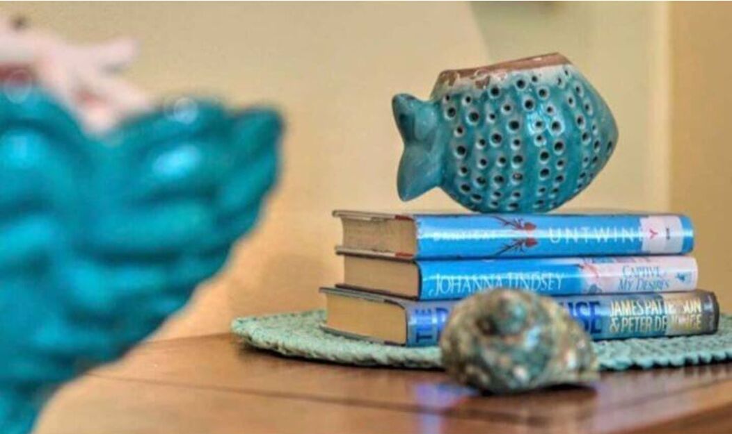 A stack of books with a ceramic fish on top.