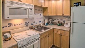 A kitchen with wooden cabinets, a white stove, a microwave, and a sink.