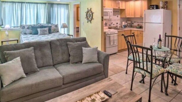 A cozy living room with a sofa, a dining table with chairs, and a kitchen area with cabinets and appliances.