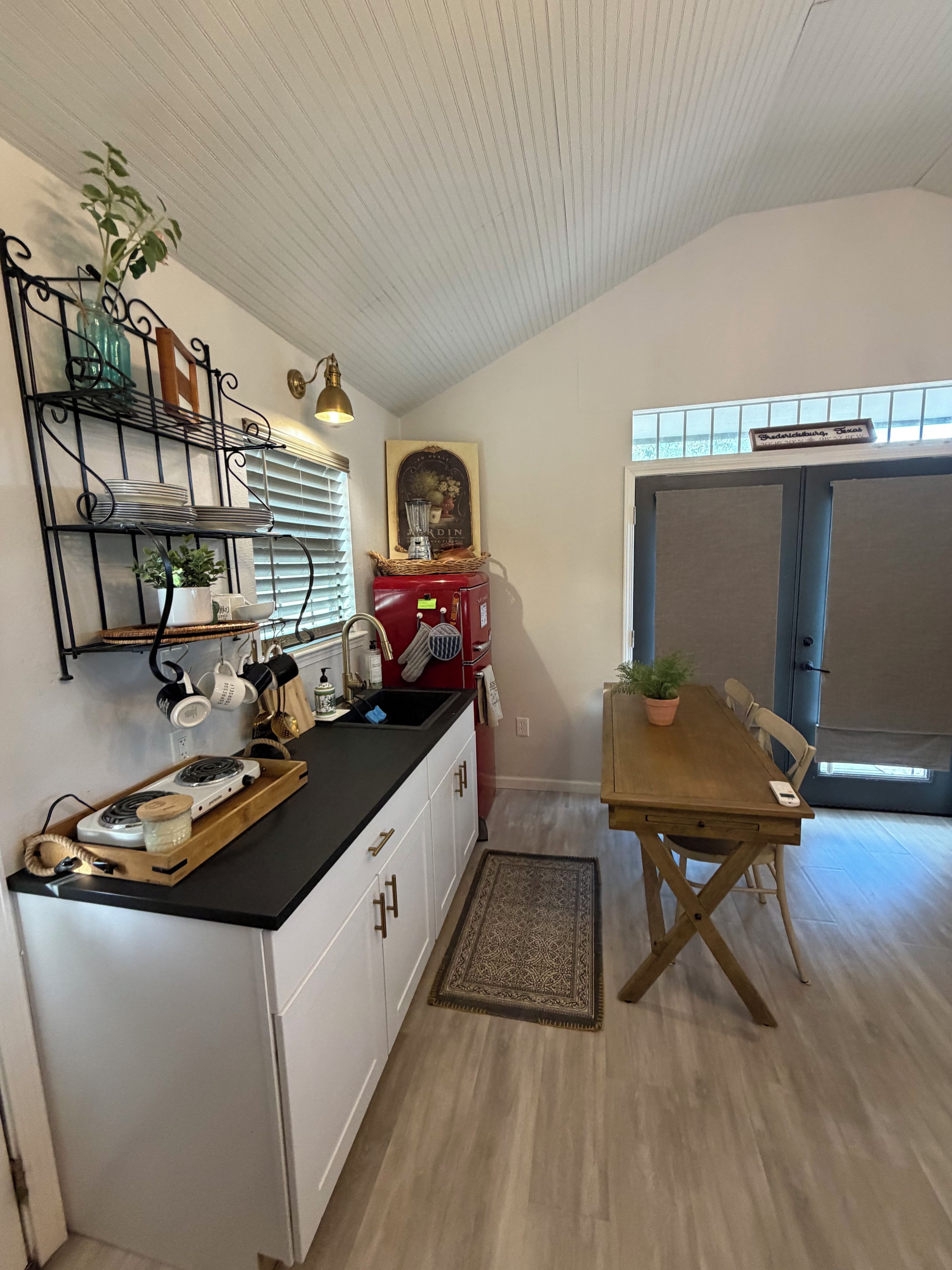 A kitchen with a black countertop, white cabinets, a red vintage stove, and a dining area with a wooden table and chairs.