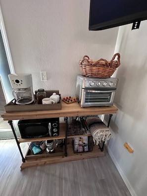 Ein Küchenbereich mit Kaffeemaschine, Toaster, Mikrowelle und Backofen auf einer Holzwand.