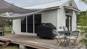 Un patio techado al aire libre con una parrilla, una mesa de comedor y sillas.