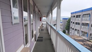 Un porticato coperto con finestre e ringhiera, che conduce a un edificio con diversi piani e balconi.