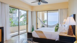 Habitación de hotel con una cama grande, ventilador de techo, vista al océano y una hamaca.