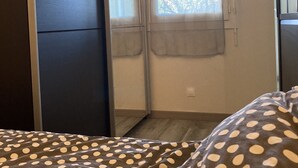 A bedroom with a bed, a window with curtains, and a wardrobe.