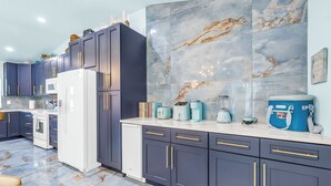 Una cocina moderna con gabinetes oscuros, un refrigerador blanco y un salpicadero de mármol.