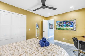 A bedroom with a bed, a ceiling fan, a painting, and a desk with a chair. - Luxury Mermaid House
 (Largo)