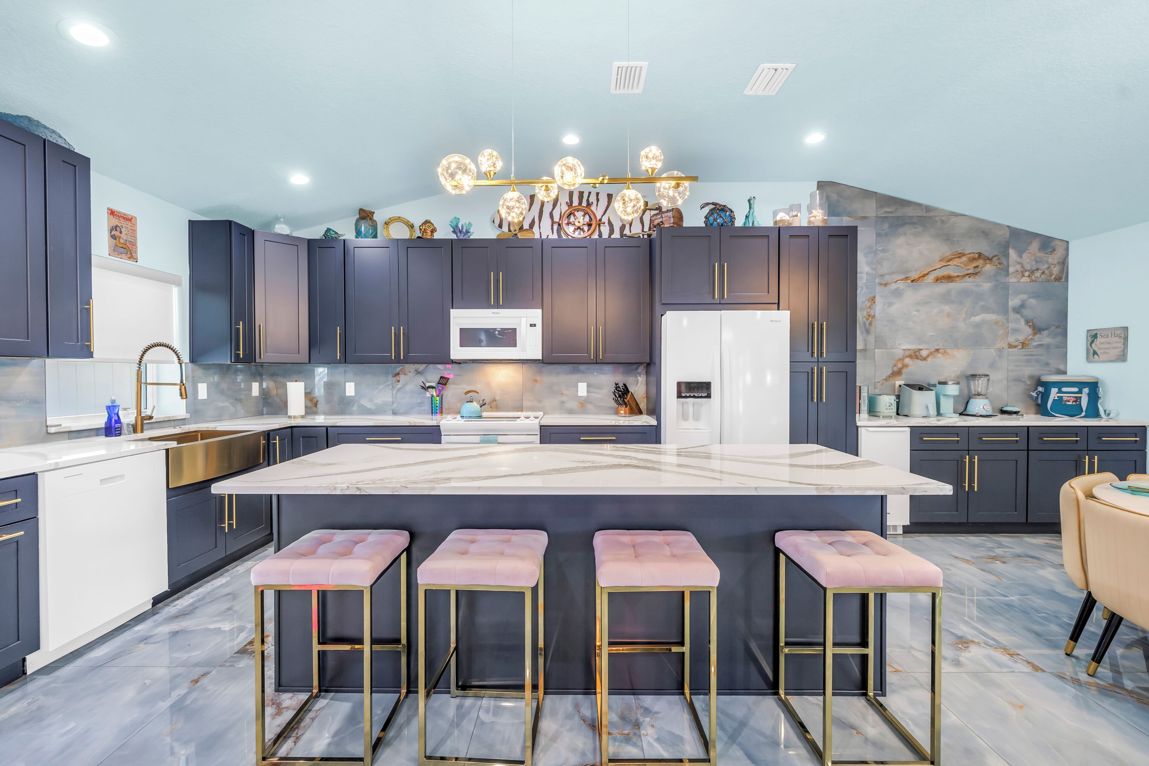 A modern kitchen with dark cabinets, a marble countertop, and a central island with bar stools.