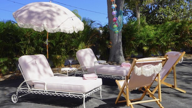 Un ensemble de fauteuils de jardin blancs avec des coussins à rayures, une petite table ronde et un parasol blanc.
