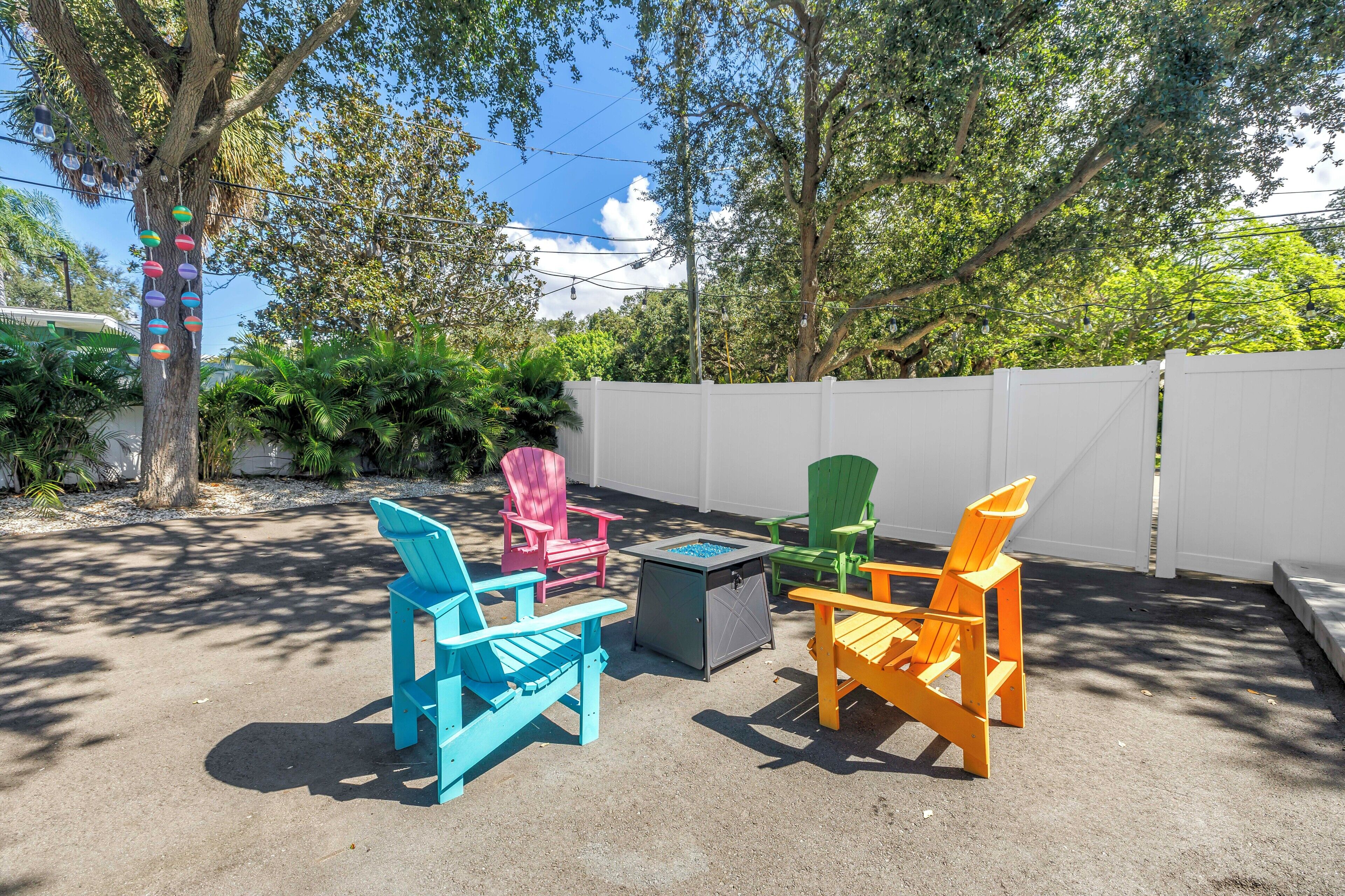 A patio area with colorful Adirondack chairs, a small table, and a fire pit.
