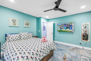 A bedroom with a bed, a ceiling fan, and artwork on the walls.
