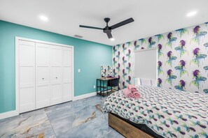 A bedroom with teal walls, a bed with a colorful fish pattern, a ceiling fan, a wardrobe, and a mirror with a fish-themed wallpaper. - Luxury Mermaid House
 (Largo)