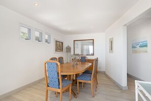 A dining area with a wooden table and chairs, a chandelier, and framed artwork on the walls.