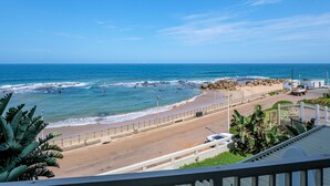 Vista de una playa con una carretera, una cerca blanca y un edificio con un letrero.