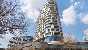 Un moderno edificio de gran altura con múltiples balcones y ventanas amplias.