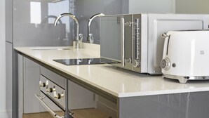 Una cocina moderna con extractor de acero inoxidable, una tostadora blanca y un lavamanos doble.