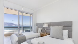 Une chambre d’hôtel avec deux lits, une vue sur l’océan et un balcon.