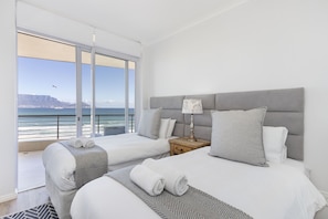 Habitación de hotel con dos camas, vista al océano y un balcón.
