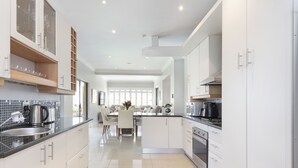 Una cocina moderna con armarios blancos, encimera negra y comedor con mesa y sillas.