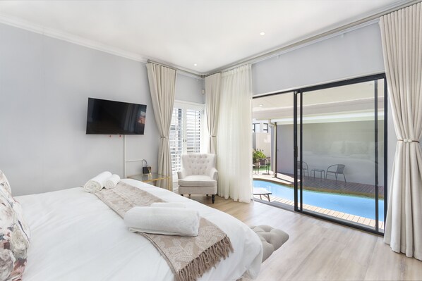 Relax in a spacious room with a large bed, flat-screen TV, and comfortable armchair.