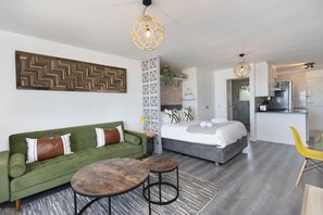 Un espacio moderno para vivir con un sofá verde, una cama, una zona de comedor y una cocina.