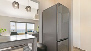 Eine moderne Küche mit einem großen, edlen Kühlschrank aus Edelstahl, einem Essbereich mit Meerblick und einem minimalistischen Design.