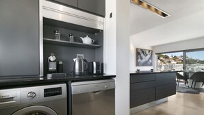 A modern kitchen with Bosch appliances, a built-in washer, and a view of a cityscape through large windows. - Seacliffe 502 - Two Bedroom Apartment, Sleeps 4 (Cape Town)