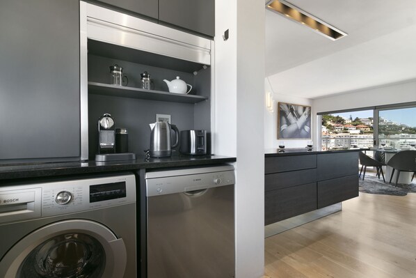 A modern kitchen with Bosch appliances, a built-in washing machine, and a view of a cityscape through large windows.