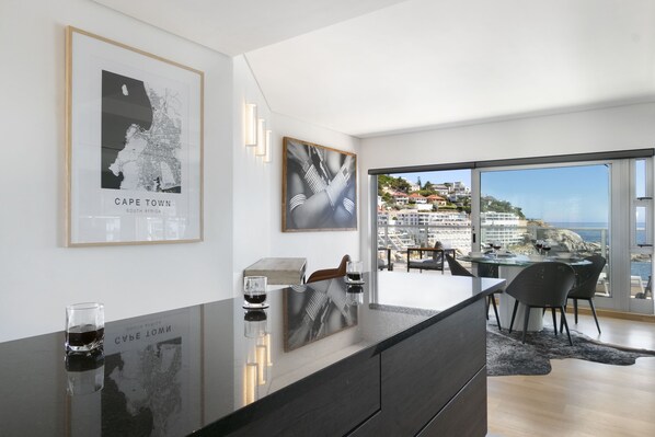 Una cocina moderna con una isla grande, obras de arte enmarcadas y vista al litoral.