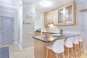 Une cuisine moderne dotée d’un îlot central, de meubles en bois et d’un mur décoré avec le motif « EAT Love ».