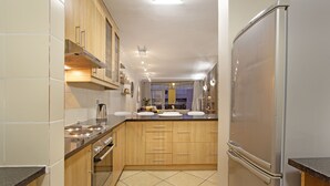 A modern kitchen with wooden cabinets, a stainless steel refrigerator, and a built-in oven.