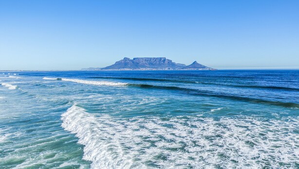 A coastal view with clear blue waters and a distant mountain.