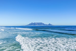 A coastal view with clear blue waters and a distant mountain.