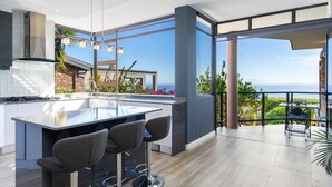 A modern kitchen with a large island, bar stools, and a view of the ocean.