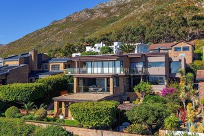 Uma casa moderna com um amplo pátio, rodeada por vegetação exuberante e uma paisagem montanhosa.