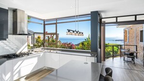 A modern kitchen with a large window overlooking a scenic view, a dining area with a view, and a built-in stove.