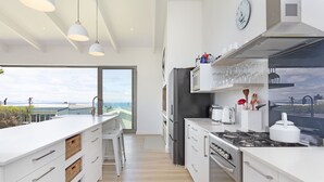 Una cocina moderna con armarios blancos, electrodomésticos de acero inoxidable y un amplio ventanal con vistas panorámicas.